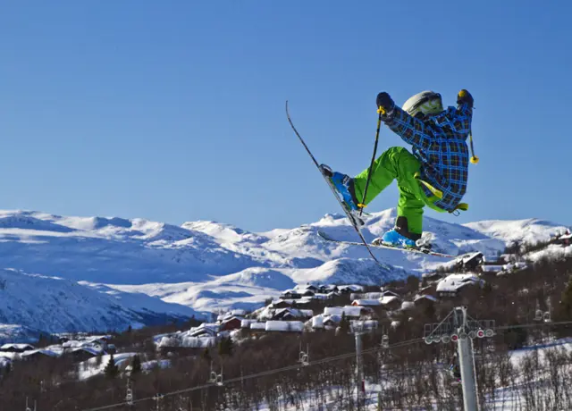 Liten gutt som hopper på alpinski